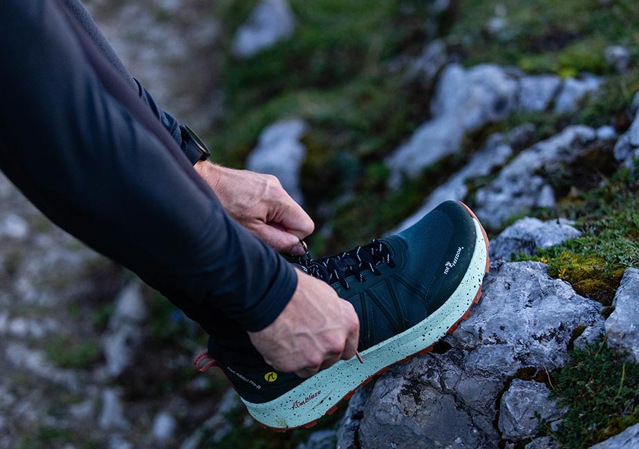 Läufer bindet seinen Joe Nimble Trail Addict Pro-R Traillaufschuh in Grün/Basil