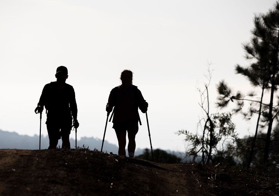 Zwei Läufer bei Sonnenuntergang in den Bergen mit dem Joe Nimble Mountain Addict Wanderschuh in schwarz/weiß